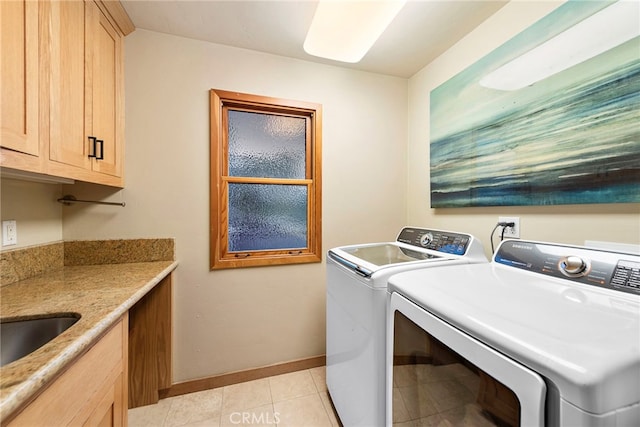 laundry area featuring washer and clothes dryer, light tile patterned floors, and cabinets