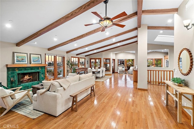 living room featuring a fireplace, vaulted ceiling with beams, light wood-type flooring, and a healthy amount of sunlight