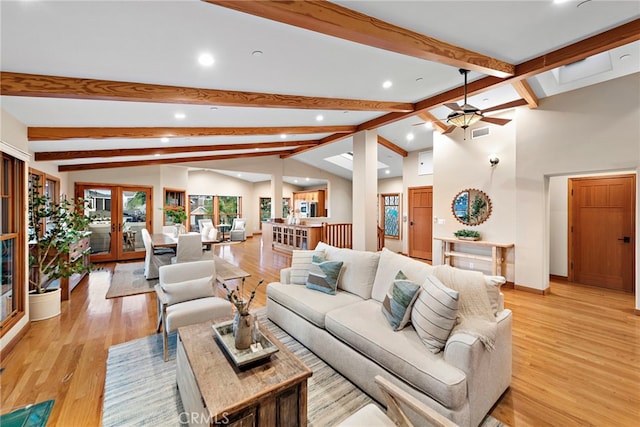 living room with french doors, light hardwood / wood-style floors, vaulted ceiling with beams, and ceiling fan