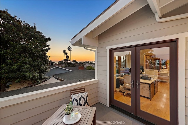 balcony at dusk featuring french doors