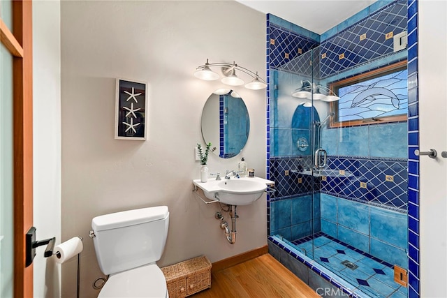 bathroom with hardwood / wood-style floors, sink, a shower with door, and toilet