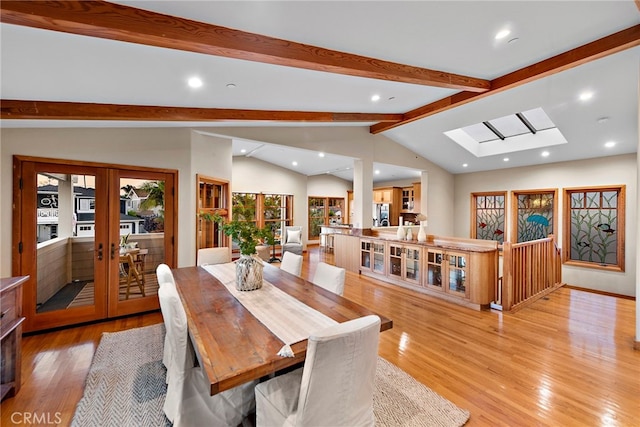 dining area with french doors, light hardwood / wood-style floors, and lofted ceiling with skylight