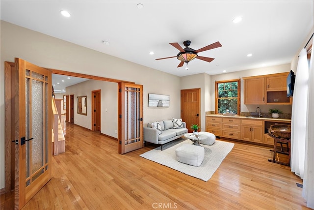 living room with light hardwood / wood-style floors, sink, and ceiling fan