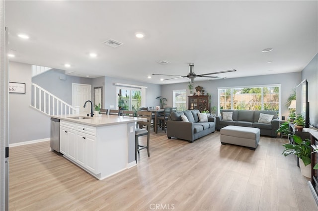 kitchen with white cabinets, plenty of natural light, stainless steel dishwasher, and a kitchen island with sink