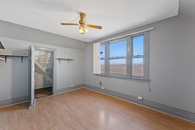 unfurnished bedroom with ceiling fan, lofted ceiling, and wood-type flooring