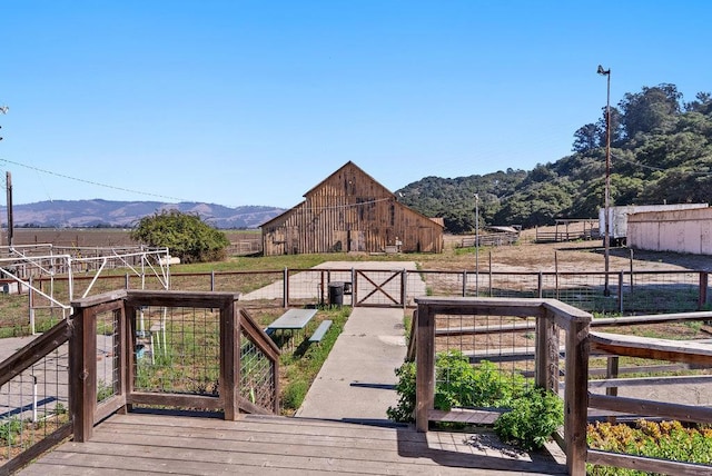 wooden terrace featuring an outbuilding, a rural view, and a mountain view