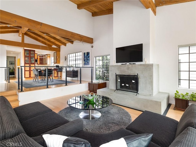 living room with beamed ceiling, a fireplace, and light hardwood / wood-style flooring