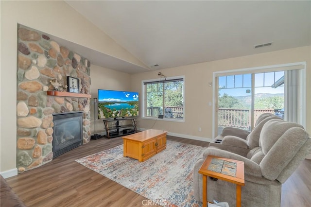 living room with wood-type flooring, a fireplace, and vaulted ceiling