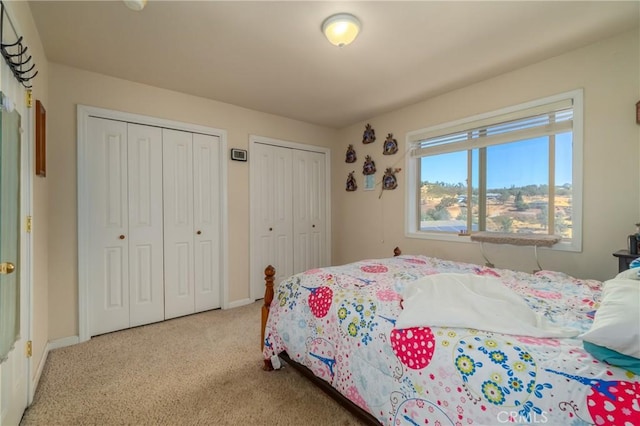 bedroom with light carpet and two closets