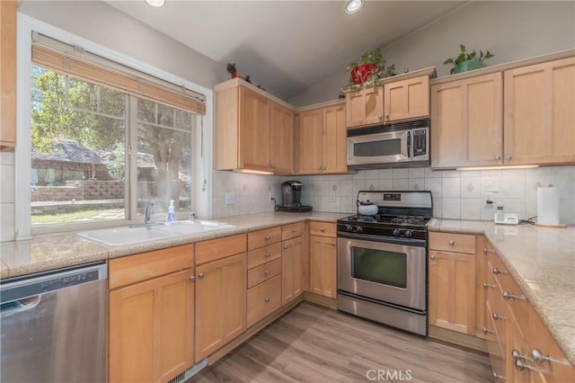 kitchen featuring plenty of natural light, light hardwood / wood-style floors, appliances with stainless steel finishes, and vaulted ceiling