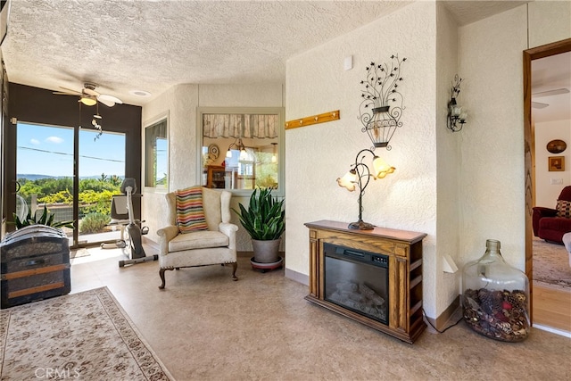 living area featuring ceiling fan and a textured ceiling