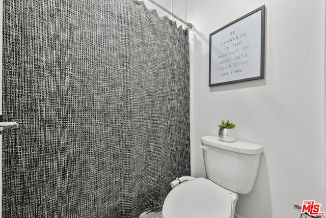 bathroom featuring toilet and a shower with shower curtain