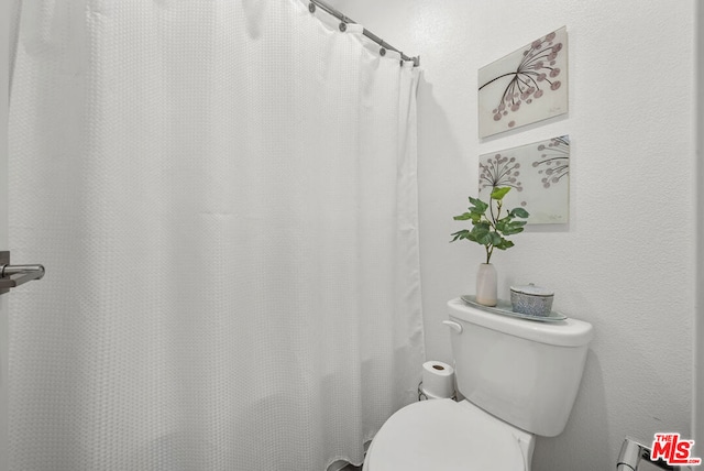 bathroom with toilet and curtained shower