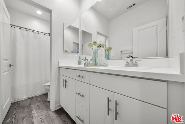 bathroom with a shower with curtain, hardwood / wood-style floors, vanity, and toilet