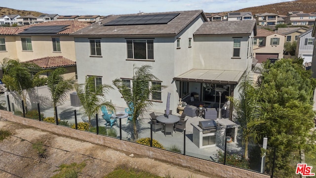 rear view of property featuring a patio area and solar panels