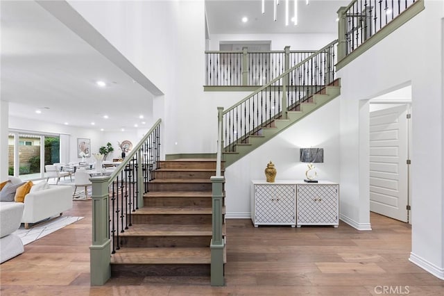 stairs featuring hardwood / wood-style floors and a high ceiling