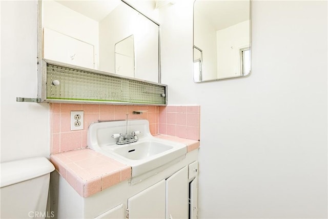 bathroom with decorative backsplash, vanity, and toilet