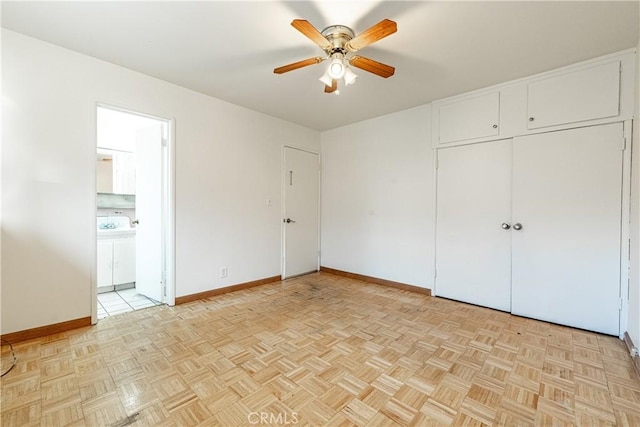 unfurnished bedroom featuring ceiling fan, ensuite bath, washer / dryer, and light parquet floors