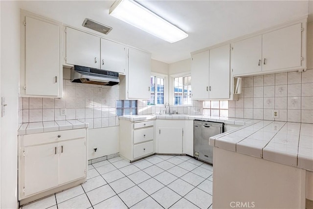 kitchen with tile countertops, white cabinetry, stainless steel dishwasher, and sink