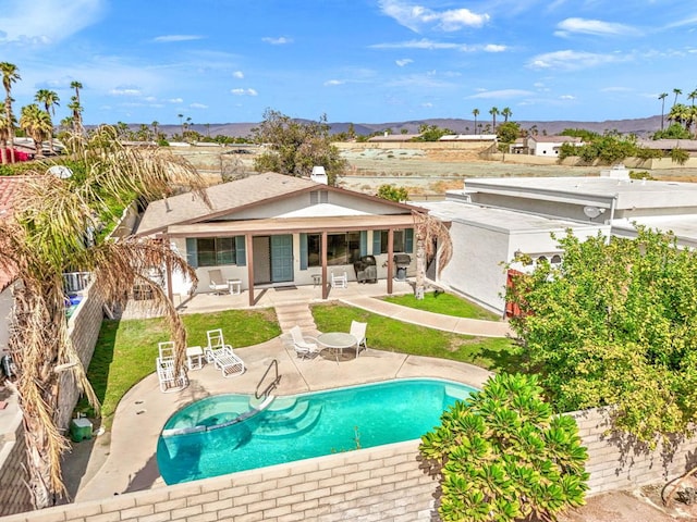 rear view of house with a mountain view, a fenced in pool, and a patio area