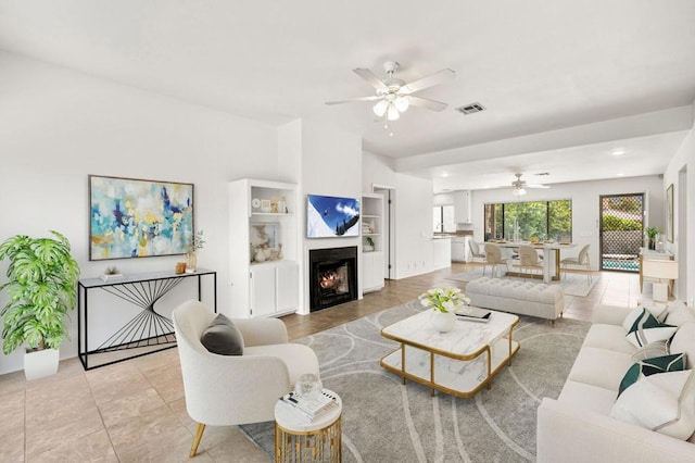 living room with ceiling fan, light tile patterned floors, and built in shelves