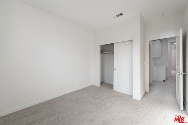 unfurnished bedroom featuring light carpet and a closet