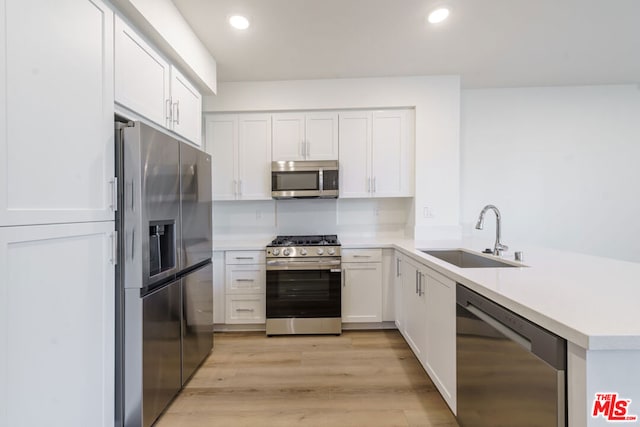 kitchen featuring sink, kitchen peninsula, white cabinets, and stainless steel appliances