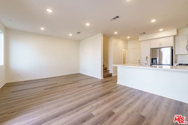 kitchen featuring sink, white cabinetry, stainless steel fridge with ice dispenser, and light hardwood / wood-style flooring