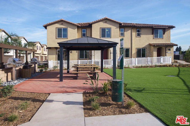 mediterranean / spanish home featuring exterior kitchen, a patio area, a gazebo, and a front lawn