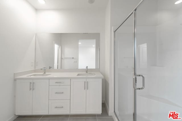 bathroom featuring a shower with door, vanity, and tile patterned flooring