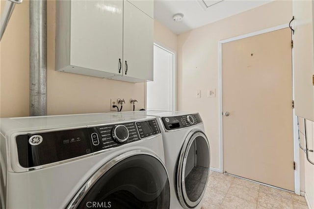 clothes washing area featuring cabinets and washing machine and clothes dryer