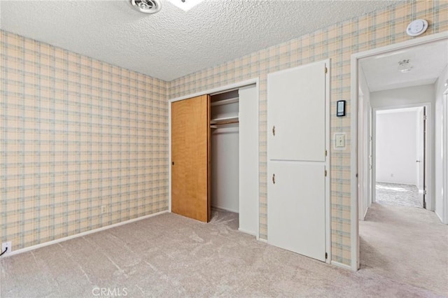 unfurnished bedroom with light carpet, a textured ceiling, and a closet