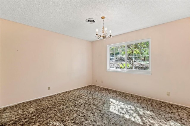 spare room with carpet floors, a textured ceiling, and a chandelier