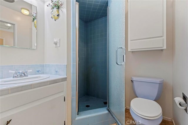 bathroom featuring tile patterned floors, vanity, toilet, and a shower with shower door