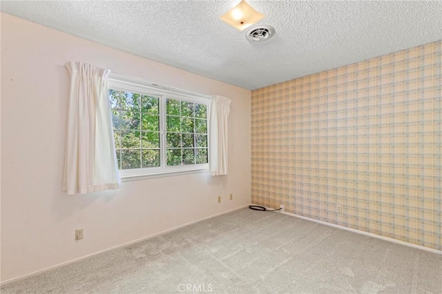 unfurnished room featuring a textured ceiling and light colored carpet