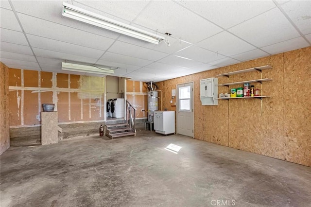 basement with secured water heater, a paneled ceiling, and washer and clothes dryer