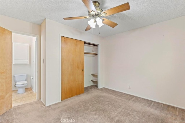 unfurnished bedroom featuring light carpet, ceiling fan, a textured ceiling, connected bathroom, and a closet