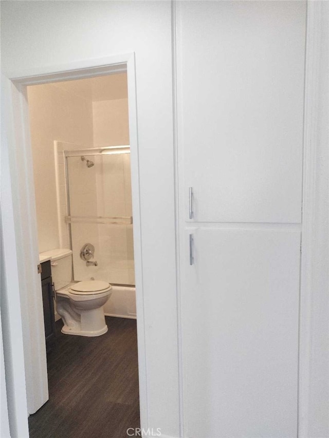 full bathroom featuring hardwood / wood-style floors, shower / bath combination with glass door, vanity, and toilet