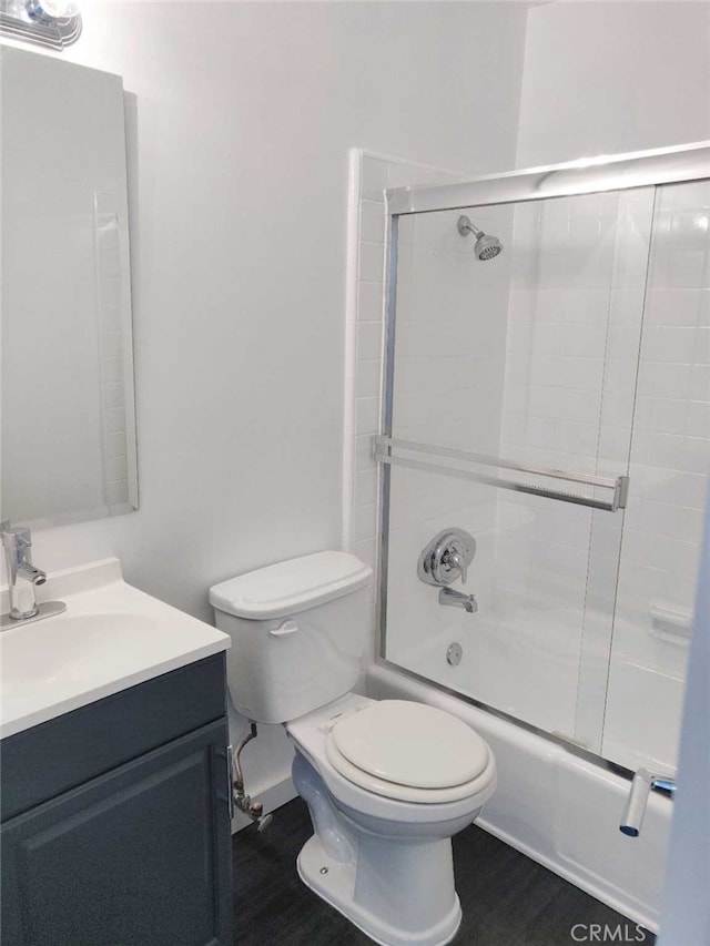 full bathroom with shower / bath combination with glass door, vanity, hardwood / wood-style floors, and toilet