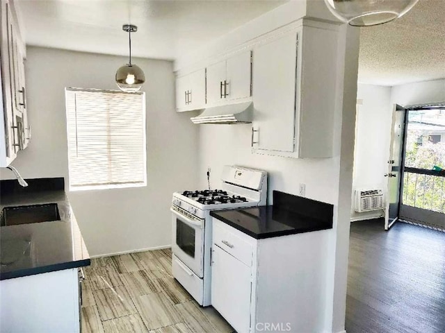 kitchen featuring white gas range, light wood-type flooring, sink, hanging light fixtures, and white cabinetry