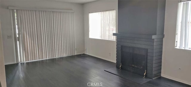 unfurnished living room featuring dark wood-type flooring and a fireplace