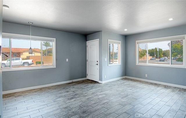 empty room featuring a textured ceiling and light wood-type flooring