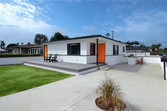 view of front facade with a patio area, exterior kitchen, and a front yard