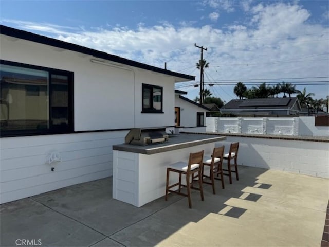 view of patio featuring exterior bar and an outdoor kitchen