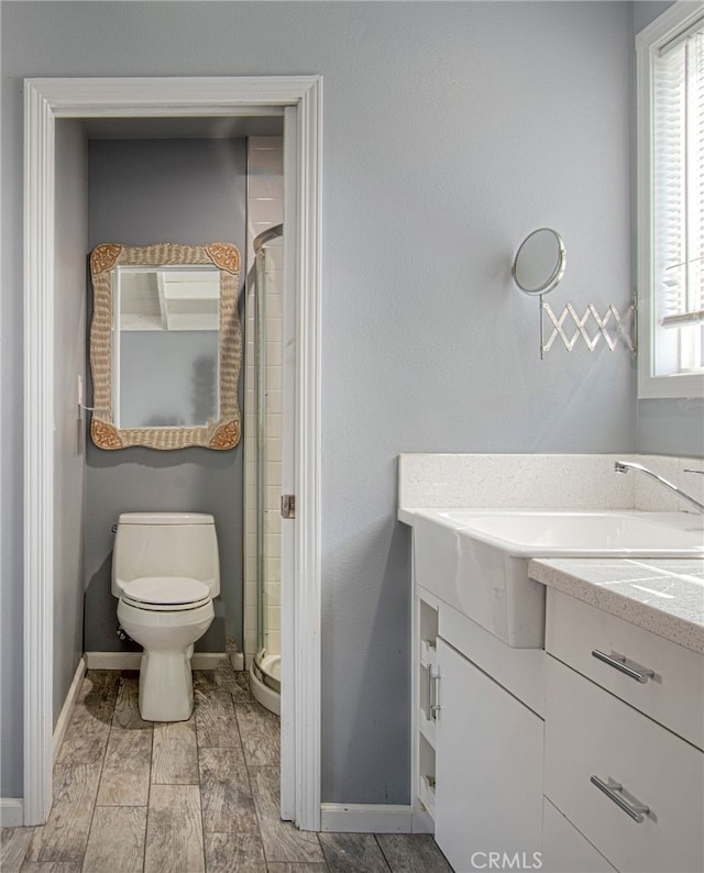 bathroom with toilet, an enclosed shower, wood-type flooring, and vanity