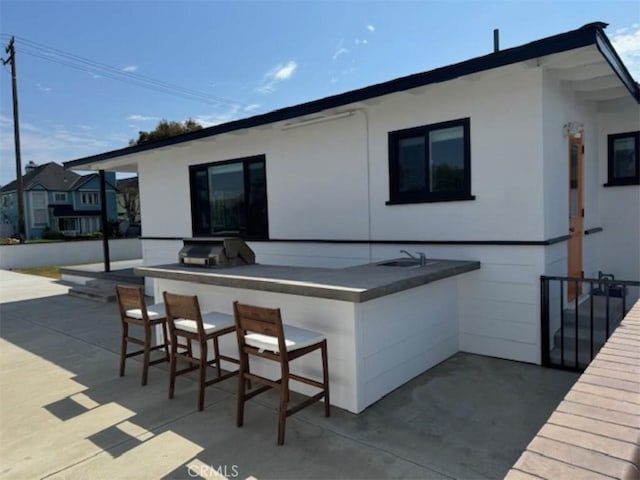 back of house featuring a bar, a patio, and an outdoor kitchen