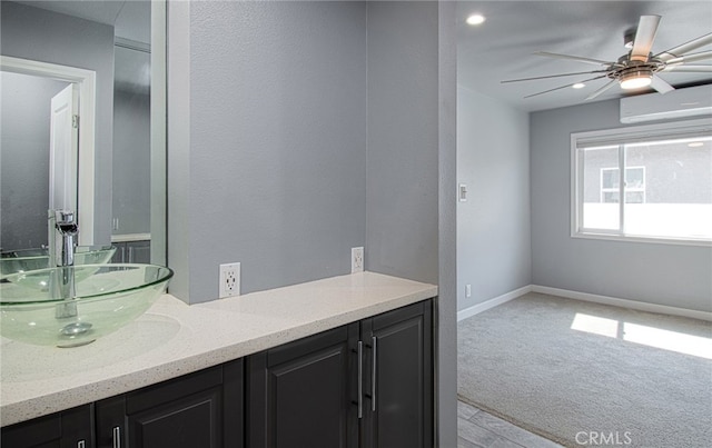 bathroom featuring a wall unit AC, ceiling fan, and vanity