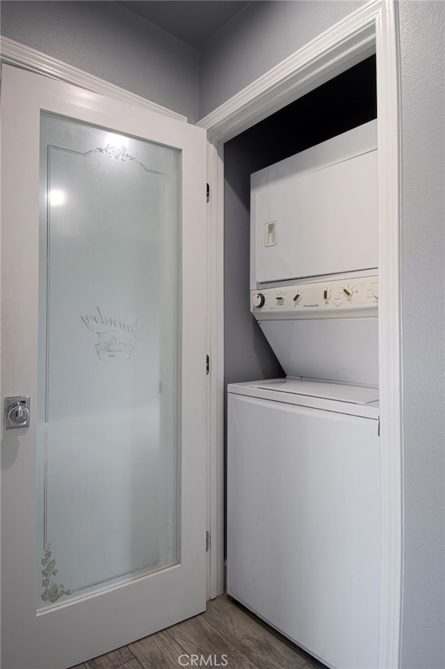 laundry room with hardwood / wood-style floors and stacked washing maching and dryer