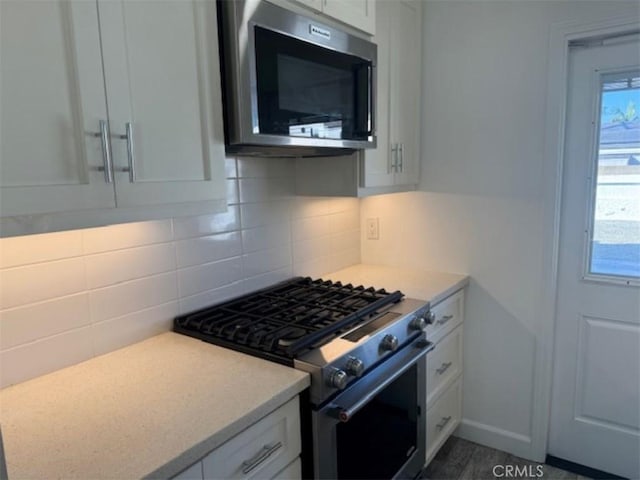 kitchen featuring white cabinets, stainless steel appliances, and tasteful backsplash