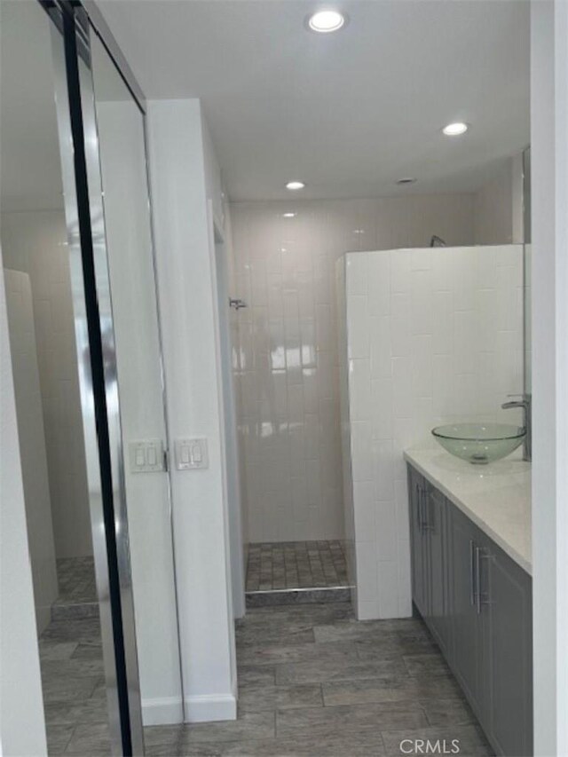 bathroom with hardwood / wood-style floors, vanity, a shower, and tile walls